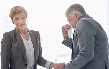 Sneeze, tissue and businessman with hand shake, deal and allergies in meeting with female person. Sick or flu and partnership for deal or success, virus and influenza for infection with clientの写真素材