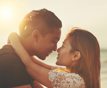 Love, couple and sunset on beach for care, support and together in nature with sunshine. Happiness, woman and man kiss outdoor for travel, adventure and holiday to Thailand for vacation in summerの写真素材