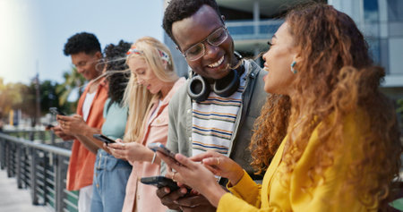 Friends, students and happy with phone at college, campus or laughing for diversity, learning or development. Gen z group, women and men on mobile app, web chat and meme on social media in universityの写真素材