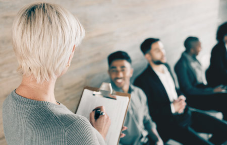 Recruitment, clipboard and hiring with people in waiting room, questions or job interview. Group, hr or documents for resume, cv or conversation with selection, hand sign or paperwork for opportunityの写真素材