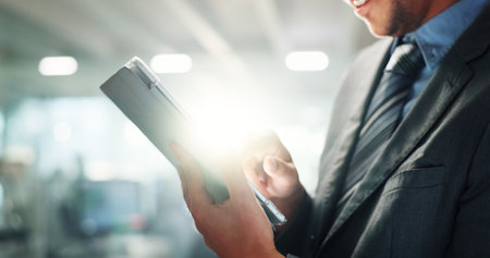 Hands, tablet and business person in office for connection, information or research with flare. App, social media and tech with professional employee in corporate workplace for email communicationの写真素材