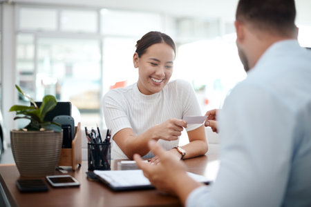 Professional, salesman and client in office with business card, contact details or information with smile. Dealership, male employee and giving company number for customer service, offer and dealの写真素材