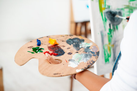 Wood palette, painting and person with brush for creativity, artwork and project with hobby or skill. Talent, canvas and artist with equipment for mixing acrylic color for craft or design in atelier.の写真素材