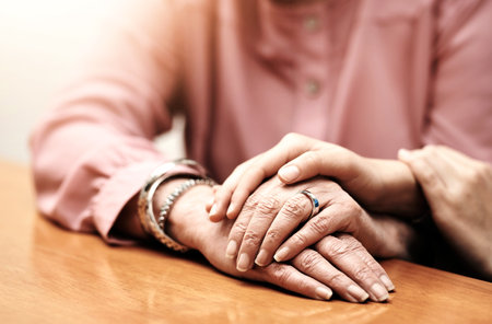Support, love and hands of people on table for empathy, compassion and comfort in hope together. Home, trust and women with gesture of kindness on desk for solidarity, forgiveness and understandingの写真素材