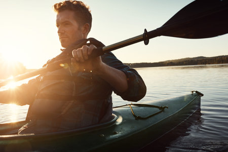 Man, paddle and nature with lake or kayak or water sports, thinking and river journey on summer vacation. Person, canoeing and happy on holiday in outdoor with sunshine, adventure and rowing for tourの写真素材
