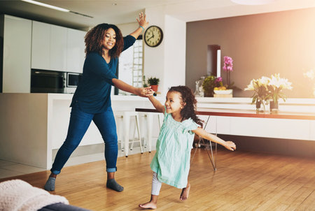 Dance, love or smile with mother and daughter in living room of home together for bonding or fun. Energy, happy or music with single parent woman and girl kid in apartment for child developmentの写真素材
