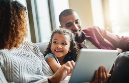 Man, woman and home with girl on tablet for learning, growth and development with online game. Family, child and ebook in living room for education, together on sofa with tech for multimedia websiteの写真素材