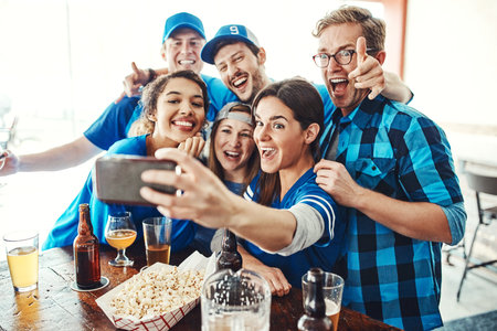 Sports, fans and happy people in bar selfie with beer, snack and celebration   together. Photography, games and group of excited friends in pub for watch party, drinks and club competitionの写真素材