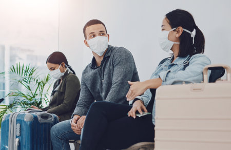 People, airport and face mask for protection, safety and PPE compliance of airline policy with post covid. Group in waiting room with luggage, suitcase and travel protocol for immigration in USAの写真素材