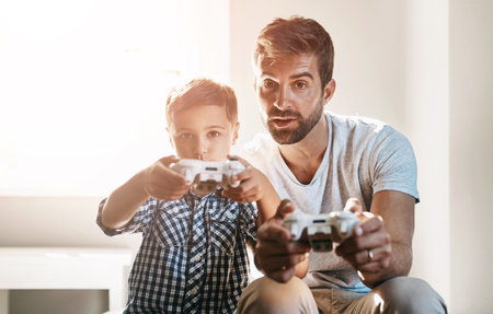 Father, son and play video game together with competition, relationship bonding and happy in home. Dad, child and gaming controller for entertainment, esports challenge and fun contest with careの写真素材