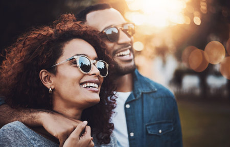 Love, hug and couple in park, sunglasses and romance with relationship, support and bonding together. Outdoor, embrace or happy man with woman, peaceful and vacation with adventure, trust or kindnessの写真素材