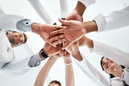 Hands stack, medical and people at hospital for healthcare support, solidarity and teamwork of workforce motivation. Staff, diversity and collaboration, trust and synergy together for low angleの写真素材