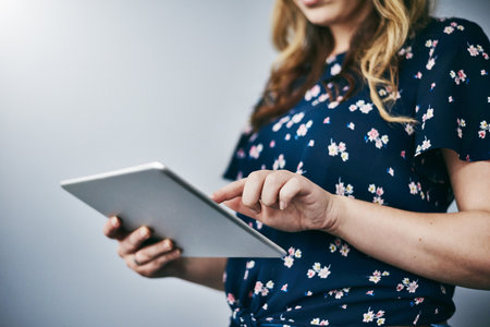 Hands, typing and woman with tablet in studio for email, contact or networking on internet search. Scroll, mockup and girl on digital app for online chat, social media or web post on white backgroundの写真素材