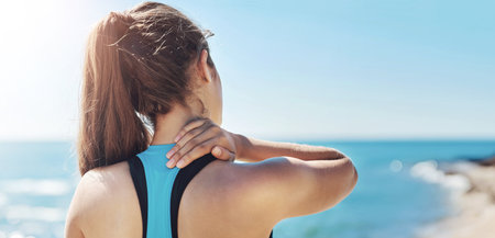 Fitness, neck pain and woman by beach with injury, muscle strain and accident from training. Sports, health and athlete with inflammation, tension and medical risk from exercise, workout and wellnessの写真素材