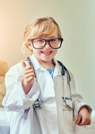 Doctor, portrait and girl child with thumbs up for young physician, agreement and future career in medicine. Healthcare, dress up and kid with good news for educational play, development or approvalの写真素材