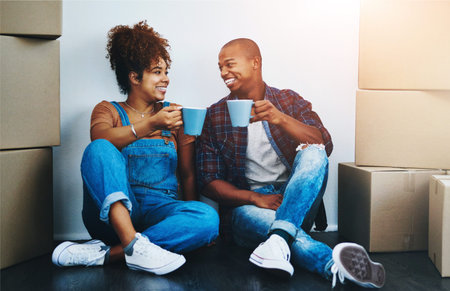 Couple, boxes and coffee on apartment floor with smile for moving, investment and rental property....