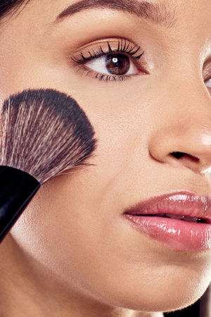 Close up, woman and brush for beauty and makeup in studio with application and cosmetics for skin....