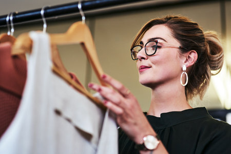 Thinking, fashion designer and woman with clothes, garments and designs in atelier or clothing business. Female tailor, dressmaker and browsing for art, design or trendy style as creative in boutiqueの写真素材