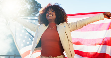 Woman, american flag and smile with celebration outdoor for national holiday, human rights or freedom. Patriot, person or happy for independence, pride or loyalty with confidence, culture or heritageの写真素材