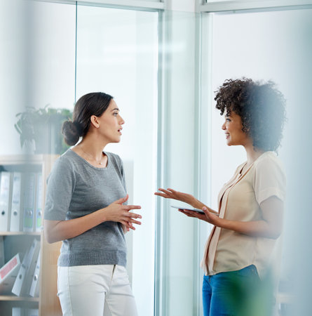 Tablet, women and talking in collaboration for project on tech in office or company as team. People, diversity and coworking for discussion, digital agency for deadline or development as colleaguesの写真素材
