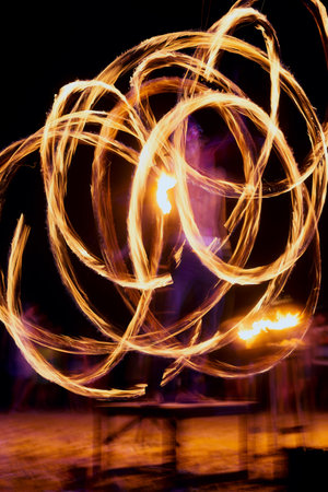 Person, fire and performance on beach with dancer for New Years celebration with smoke and adventure. Performer, light and streak at ocean or Thailand party for long exposure show, art or nightlifeの写真素材