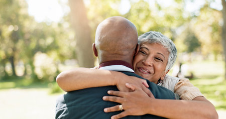 Love, hug and senior couple in park for walk, calm and talking in retirement in nature or forest. Partner, diverse and support or trust for man and female person, care and conversation togetherの写真素材