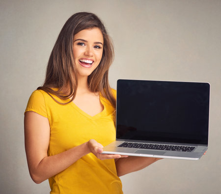 Woman, laptop screen and portrait for advertising, smile for promotion or isolated white background. Computer, girl or marketing by brand ambassador with technology, presentation and app in studioの写真素材