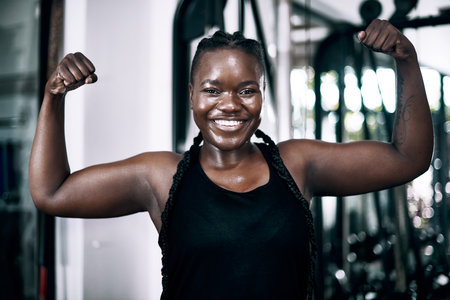 Black woman, portrait and muscle for fitness, arms and confidence for sports workout. Smile, bodybuilder and cardio for body health with flex, active and challenge for African person in studioの写真素材