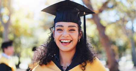 Excited girl, portrait and graduation with hat in nature for outdoor ceremony, scholarship or qualification. Happy female person, student or graduate with smile for education or higher certificateの写真素材