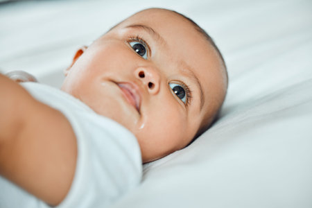 Baby, relax and thinking on bed in morning for health, development and rest in family home. Close...