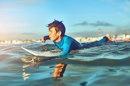 Kid, waves and surfing at beach for holiday, sports and wellness with board, blue sky and swimsuit....