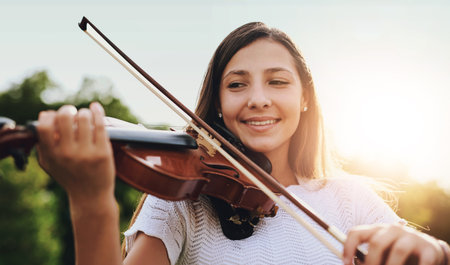 Face, smile and violin with girl in garden to practice for performance, recital or rehearsal. Art, instrument and music with happy child outdoor in backyard for creative, education or learningの写真素材