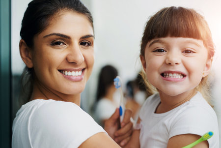 Mother, child and brushing teeth portrait for dental hygiene, health and wellness learning with smile. Home, bathroom and young girl with toothbrush, teeth and cleaning at morning with love and careの写真素材