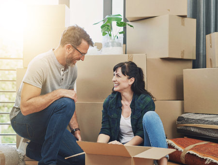 Moving, smile and couple with boxes in new home unpacking together in living room with happiness....
