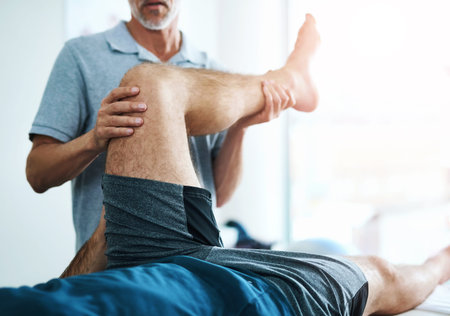 Healthcare, leg and physiotherapist with man patient in clinic for healing, rehabilitation or...