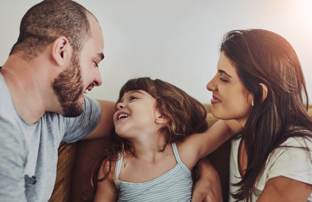 Smile, girl and parents on couch with love for bonding, relationship trust and development in family home. Mom, dad and happy daughter on sofa with support for growth, calm weekend and relax togetherの写真素材