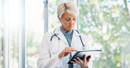 Healthcare, mature doctor and typing on tablet for medical treatment, cure and reading online....