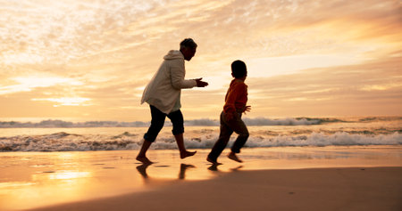 Dad, son and running on beach at sunset for family bonding, travel for wellness with games. Father, boy child and together by ocean with sand on vacation, fun adventure or freedom in Indonesiaの写真素材