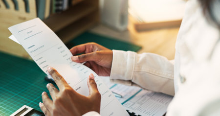 Hands, receipt and document for accounting in home office for reading, review or taxes with remote work. Person, paperwork and financial admin for check, audit or balance books at apartment in Mumbaiの写真素材