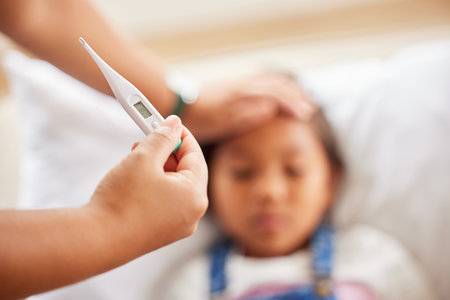 Girl, hand and thermometer for illness in home, sick and tool to monitor temperature in bedroom. Female person, daughter and parent to check for virus on forehead, fatigue and infection or diseaseの写真素材
