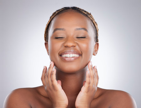 Natural, beauty and black woman or smile with skincare in studio with smooth skin, facial results and cosmetics. Model, person and happy with wellness, self care and glow treatment on gray backgroundの写真素材
