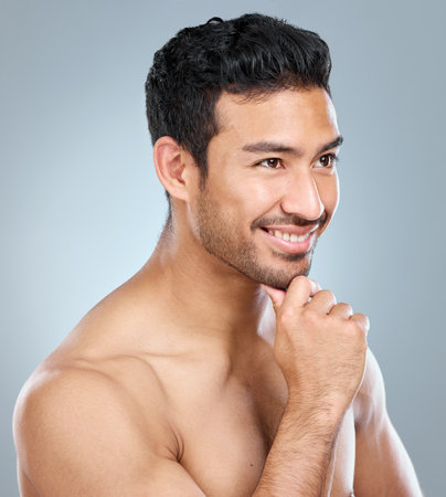 Happy man, thinking and hand in studio for dermatology for grooming and pride for glow. Male model, memory and inspiration for luxury treatment, shine and routine for clean face by gray backgroundの写真素材
