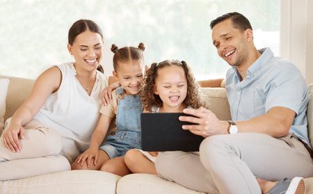Tablet, laugh and family on couch for series, online or digital entertainment for children. Funny, comedy or streaming for internet subscription, married couple or girls on sofa for bonding and movieの写真素材