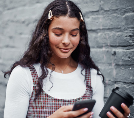 Girl, phone and teenager on social media in outdoor, communication and coffee cup for travel. Female person, notification and tea for journey in city, post update and surfing website or internetの写真素材
