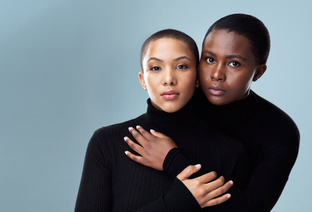 Women, couple hug and portrait for fashion in studio with pride for style inspiration and care. Lesbian, lgbtq community and friends or partner for winter trend or outfit together by gray backgroundの写真素材
