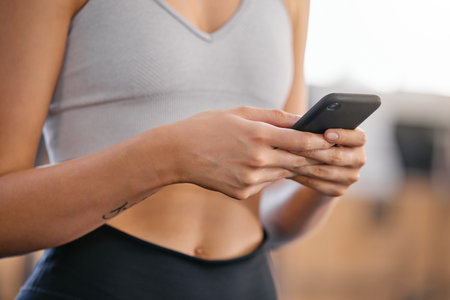 Hands, phone and woman in gym on fitness mobile app browsing for body building workout routine. Health, research and female athlete with cellphone for exercise tutorial online in sports center.の写真素材