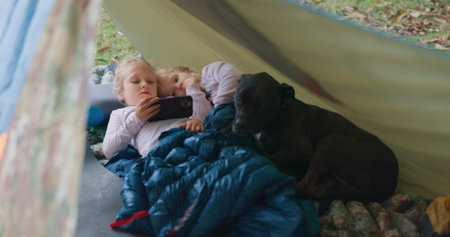Children, relax and phone for camping outdoor with watching movies, bonding and streaming videos in...