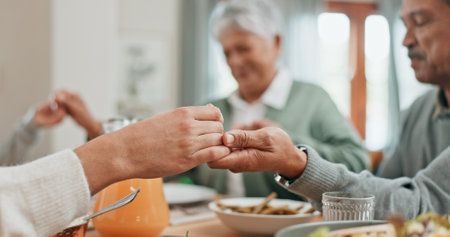 Family, home and pray for dinner in table with food for grace, grateful and gratitude. People, respect and holding hands with bonding for love, support and care on thanksgiving gathering or reunionの写真素材