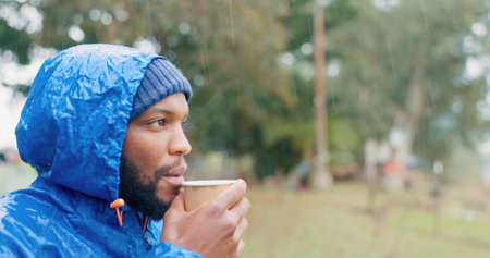Coffee, thinking and black man drinking outdoor in winter storm as person for hiking, travel and relax. Beverage, peace and mindfulness in nature for adventure, camping and rain with latte as touristの写真素材