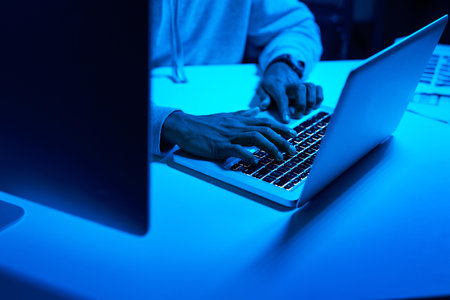 Hands, fraud or hacker stealing on laptop for cybercrime scam, malware or phishing online data in dark. Programmer, person or pc software update on tech for hacking private server on website in nightの写真素材